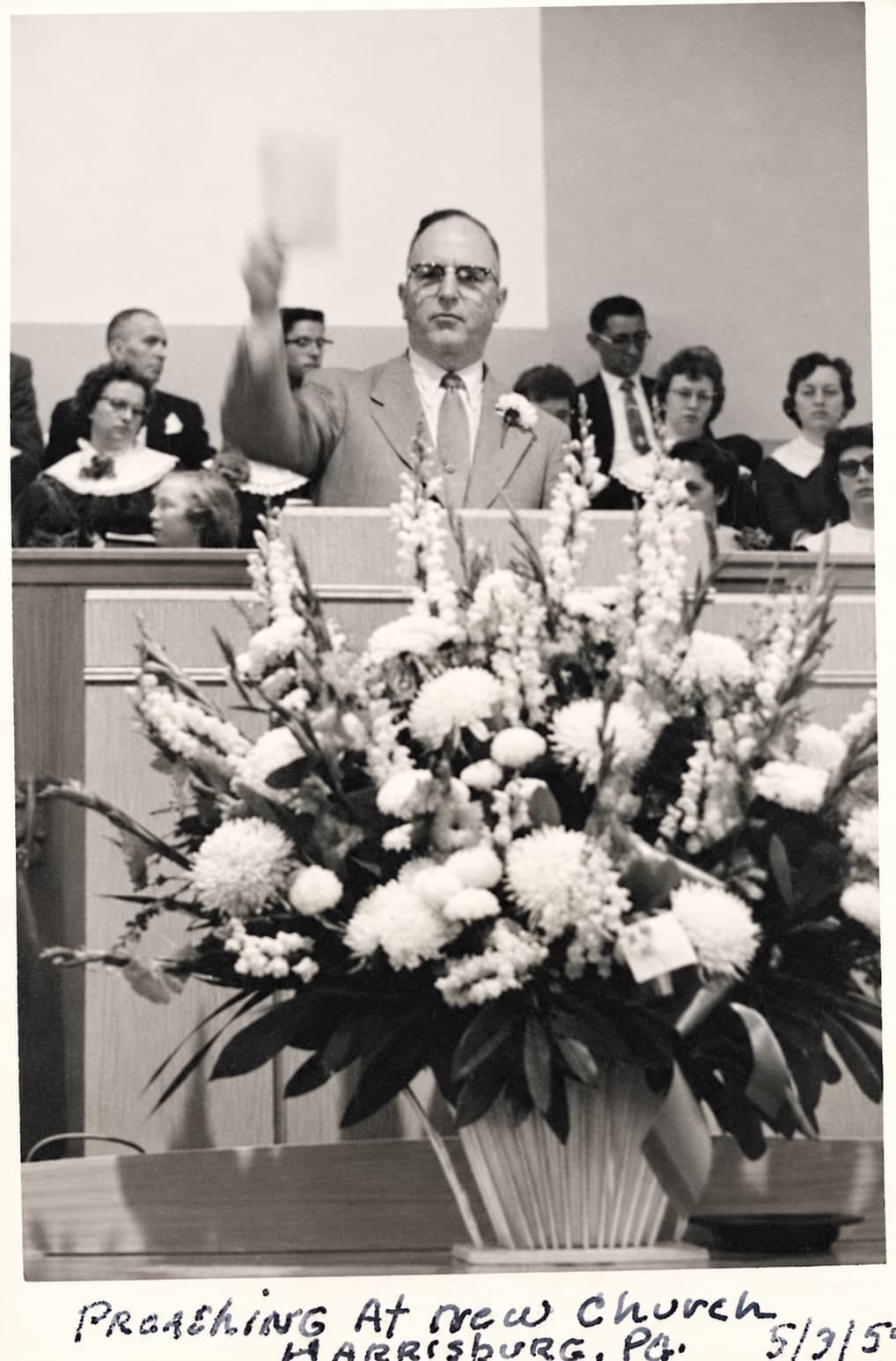 A pastor preaching behind a large flower arrangement at the new Green Street church, May 3, 1959.
