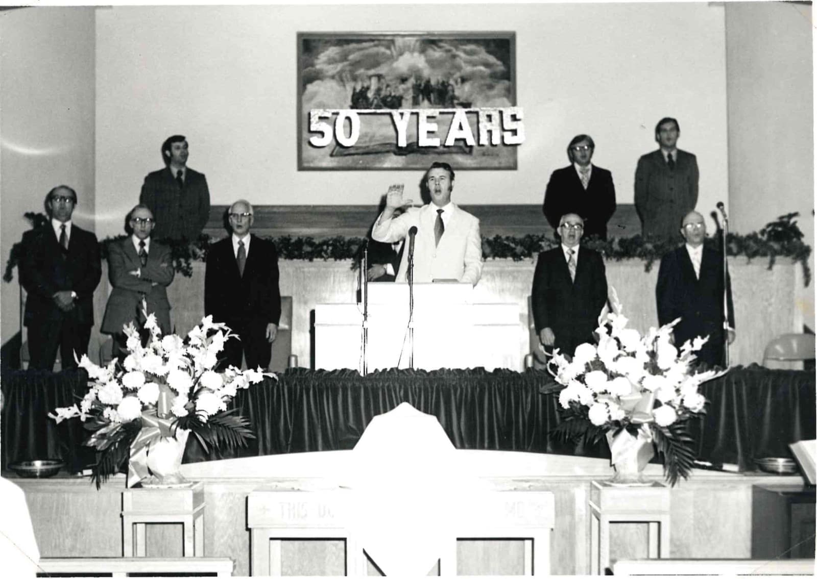 Ministers standing on the platform beneath a banner reading 50 YEARS.